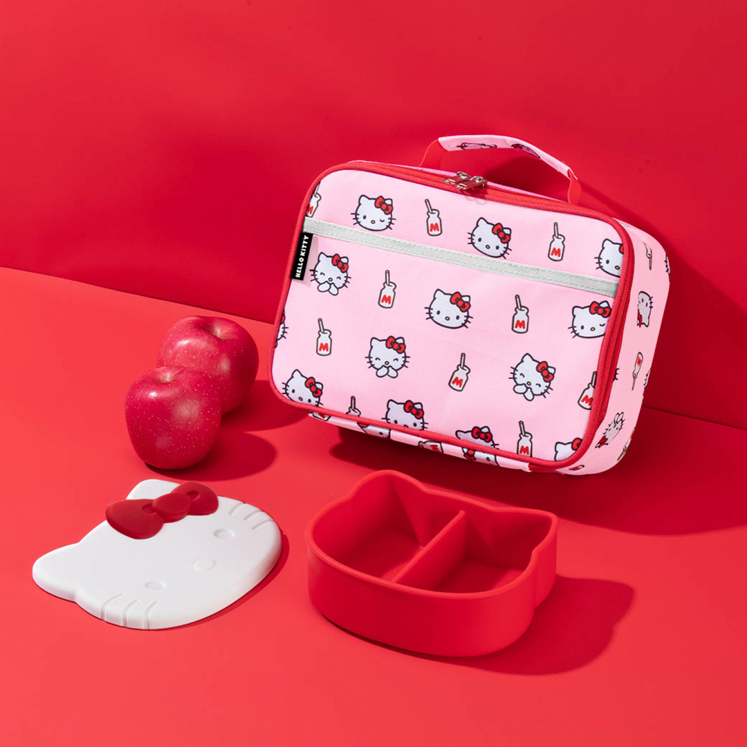 Hello Kitty-themed lunch bag, bento box, and apple on a red background, bento buzz