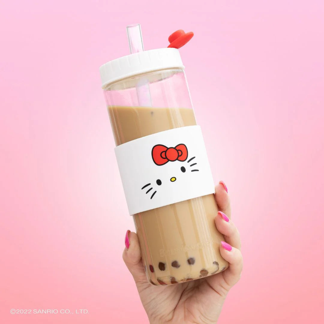 Hand holding a bubble tea with a Hello Kitty Bobblware tumbler against a pink background. Bento Buzz.